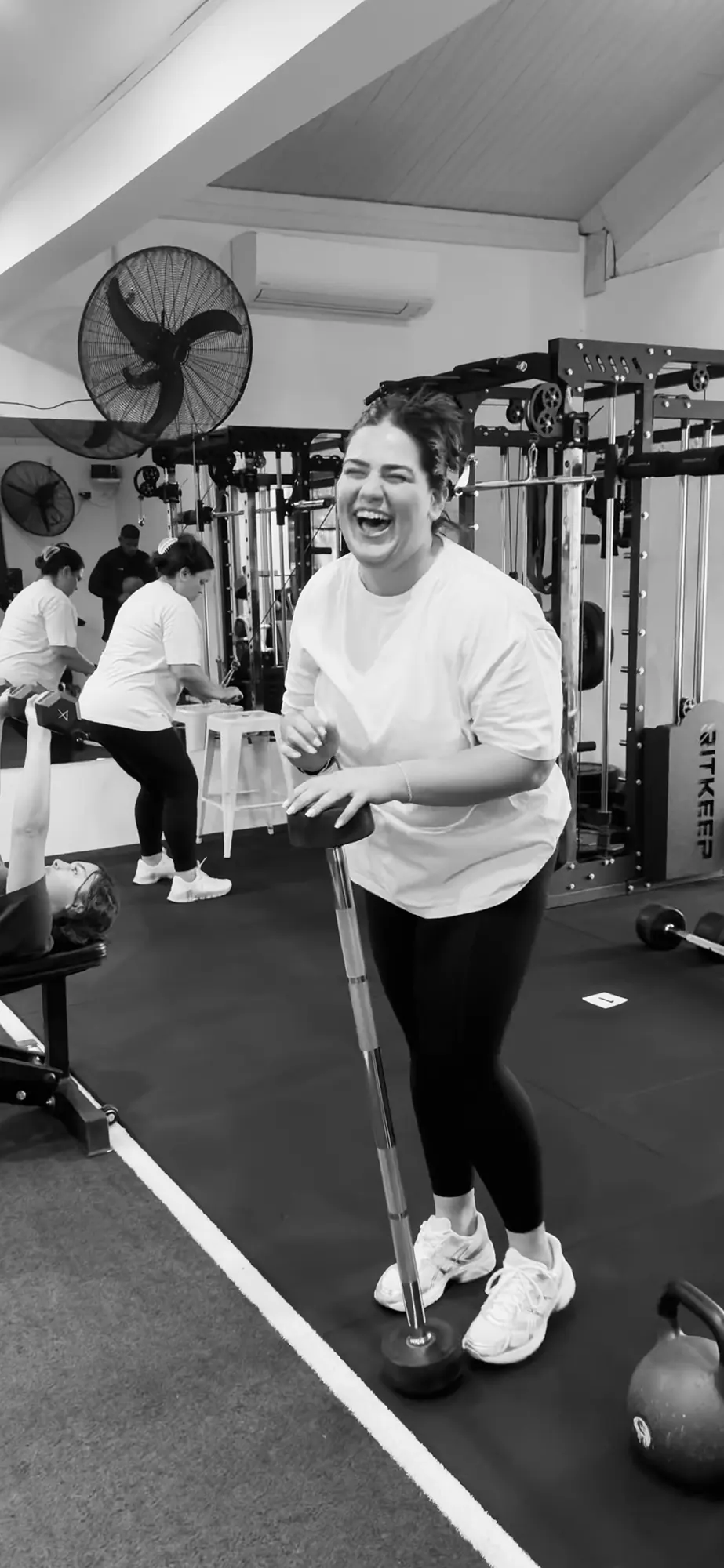 An LNPT member laughs beside strength equipment during a session.