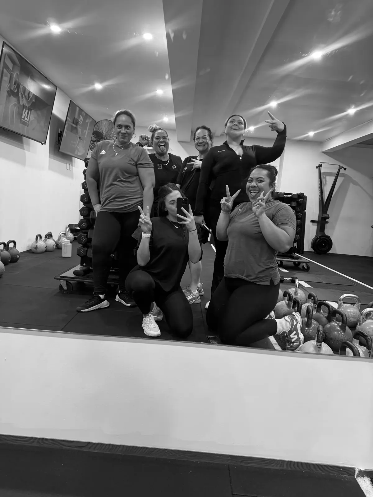 Women at LNPT smile and pose together in the studio mirror.