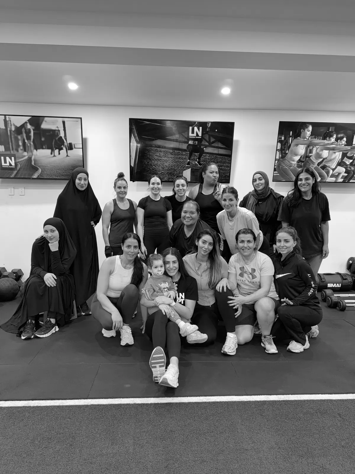 A women’s group at LNPT poses together at the studio, with a child among the group.