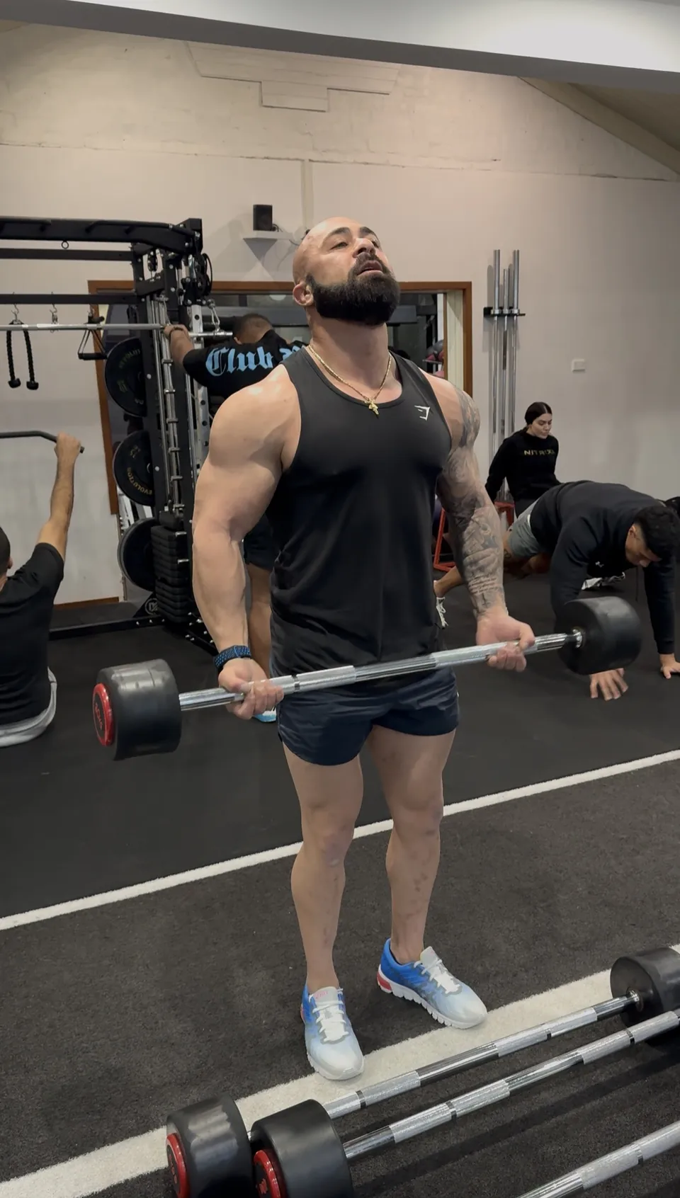 Man completing a standing barbell curl in the LNPT training studio.